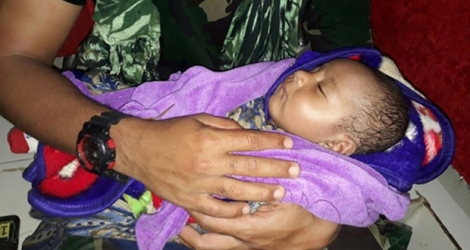 Un soldat indonésien tient dans ses bras un bébé rescapé des inondations qui ont frappé la province indonésienne de Papouasie le 17 mars 2019.