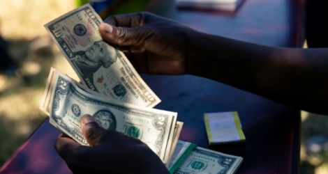 Un agent de sécurité compte de petites coupures de dollar le 13 mars 2019 à Mutoko, au Zimbabwe.