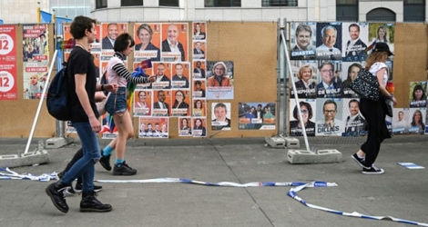 Des passants devant des affiches électorales pour les scrutins du 26 mai 2019 en Belgique (photo prise le 18 mai 2019 à Bruxelles)