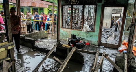 A Binjai en Indonésie, des voisins contemplent une maison où était installée une petite fabrique d'allumettes et dont l'incendie, le 21 juin 2019, a fait au moins 30 morts dont des enfants.