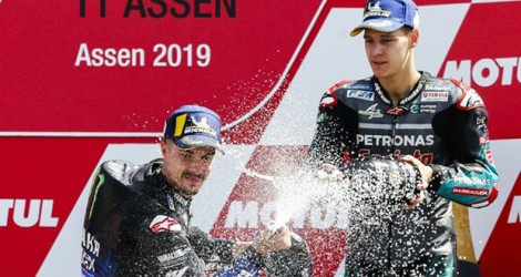 L'Espagnol Maverick Vinales (g), vainqueur du GP des Pays-Bas, sabre le champagne au côté du Français Fabio Quartararo, 3e, sur le circuit d'Assen, le 30 juin 2019.