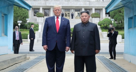Photo fournie le 1er juillet 2019 par l'agence nord-coréenne Kcna du dirigeant nord-coréen Kim Jong Un (d) et le président américain Donald Trump se tenant au nord de la ligne de démarcation entre les deux Corées, le 30 juin 2019 à Panmunjom.