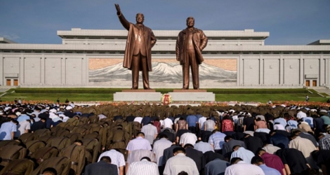 La foule s'incline devant les statues des dirigeants nord-coréens défunts Kim Il Sung et Kim Jong Il à l'occasion du 25e anniversaire de la mort de Kim Il Sung, à Pyongyang le 8 juillet 2019.