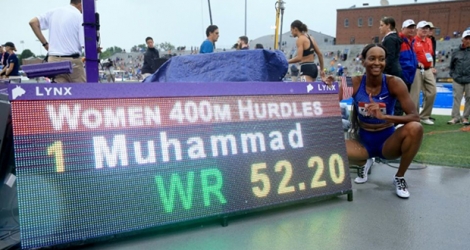 Dalilah Muhammad (d) pose à côté du panneau affichant son record du monde du 400 m haies aux Chpts des Etats-Unis, le 28 juillet 2019 à Des Moines dans l'Iowa.