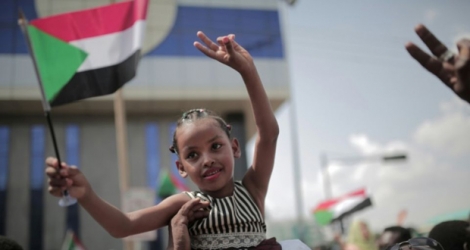 Une petite fille soudanaise agite le drapeau soudanais le 17 août 2019 à Khartoum après la signature d'un accord clé entre les généraux au pouvoir et les leaders du mouvement de contestation.
