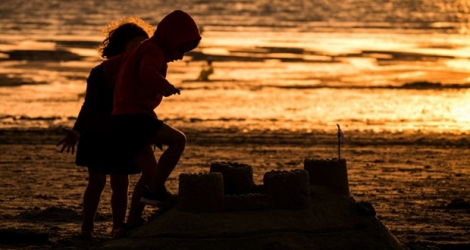 Des enfants construisent un château de sable à Gouville-sur-Mer, le 6 août 2019.