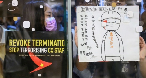 Une manifestante colle des affiches à l'extérieur d'un centre commercial à Hong Kong lors d'une manifestation de soutien aux salariés de la compagnie aérienne, le 28 août 2019.