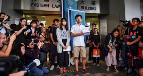 Agnes Chow (g) et Joshua Wong, figures du mouvement pro-démocratie hongkongais, montrent aux journalistes les charges retenues contre eux, après leur libération sous caution, le 30 août 2019 à Hong Kong.