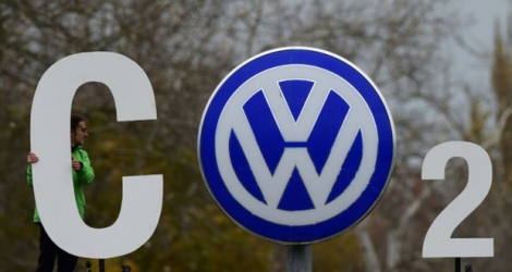 Montage réalisé par un militant de Greenpeace autour du logo du constructeur automobile allemand sur la carosserie d'une voiture VW garée devant le quartier général de Volkswagen, à Wolfsburg le 9 novembre 2015.