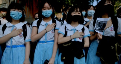 Des camarades de classe de Tsang Chi-kin, 18 ans, blessé la veille par un tir de la police au niveau du torse, manifestent devant leur école en plaçant leur main sur leur poitrine en signe de protestation, à Hong Kong le 2 octobre 2019.