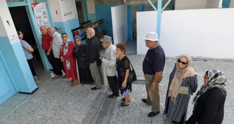 Des Tunisiens font la queue à l'entrée d'un bureau de vote, à Tunis le 13 octobre 2019, jour du second tour de la présidentielle.