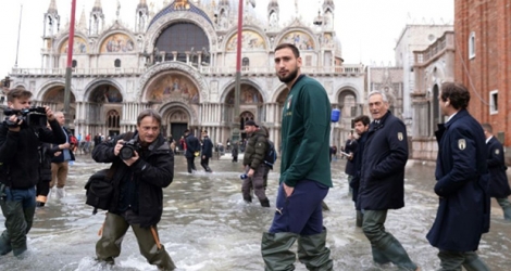 Le gardien de but du Milan AC Gianluigi Donnarumma marche sur la place Saint-Marc inondée à Venise le 16 novembre 2019.