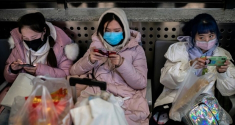Des voyageurs protégés par des masques sont à la gare de Pékin le 24 janvier 2020 prets à prendre le train pour le nouvel an chinois.