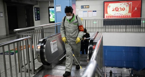 Un employé muni d'un masque de protection vaporise un produit désinfectant dans une station de métro, à Pékin le 31 janvier 2020.