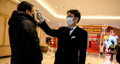 Un employé prend la température d'un passant dans un centre commercial de Shanghai, le 8 février 2020.