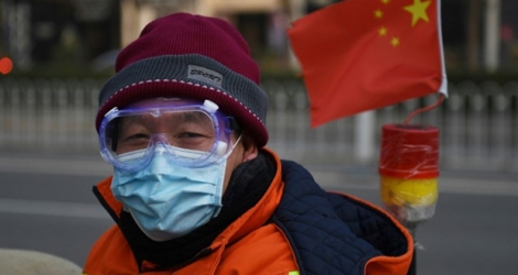 Un homme portant un masque et des lunettes de protection, dans une rue de Pékin le 11 février 2020.