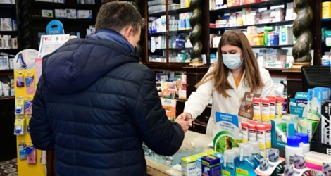 Une pharmacienne équippée d'un masque respiratoire sert un client le 22 février 2020 à Codogno, en Italie.
