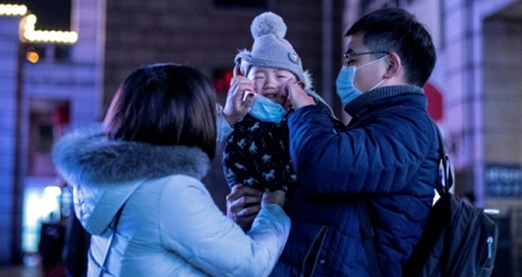 En Chine, des parents mettent un masque protecteur à leur bébé à Pékin, le 23 janvier 2020.