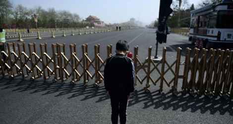 Un jeune garçon rend hommage aux morts du coronavirus lors d'une moment de recueillement national, à Pékin place Tiananmen, le 4 avril 2020.