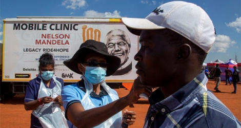 Un agent de santé vérifie la température d'un homme pour un dépistage et un test au COVID-19 à Lenasia South, sud de Johannesburg, Afrique du Sud, le mardi 21 avril 2020, lors d'une campagne visant à lutter contre la propagation du coronavirus.