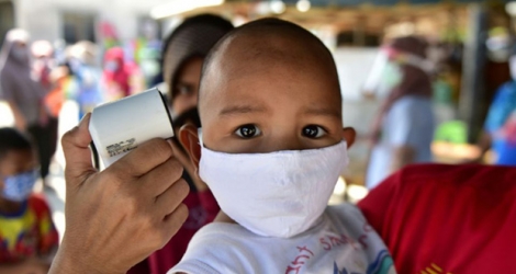 Vérification de la température d'un enfant, masqué, en Thaïlande dans la cadre de la prévention du Covid-19, le 17 avril 2020.