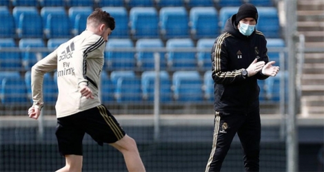 Zidane donnant des instructions en étant protégé par un masque chirurgical et des gants en plastique.