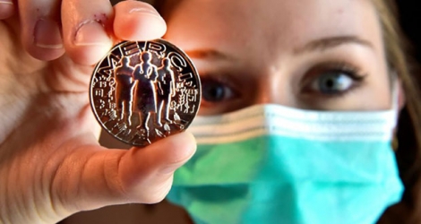 Un membre du personnel soignant montre la médaille créée par la Monnaie de Paris, en hommage aux corps médical, éboueurs, caissiers, agriculteurs etc., le 15 mai 2020 à Pessac, en Gironde.