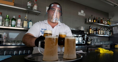 Un serveur protégé par une visière sert des bières dans un bar de Valence (Espagne), le 19 mai 2020. 