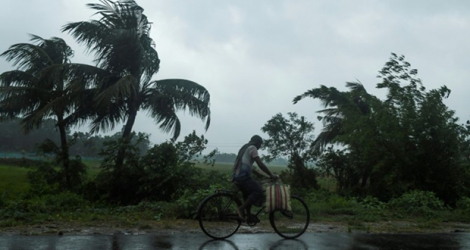 Un homme à vélo sous la pluie, avant l'arrivée du cyclone Amphan, le 20 mai 2020 à Midhapore, en Inde.