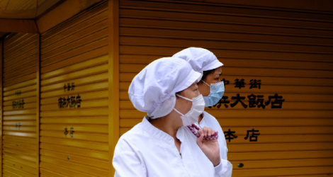 Des employés de restaurants portant des masques traversent le quartier chinois de Yokohama