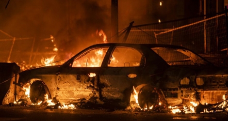 Une voiture incendiée lors de heurts entre la police et des manifestants à Minneapolis le 27 mai 2020, suite à la mort d'un homme noir après son interpellation musclée.
