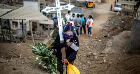 Une femme porte une croix lors des funérailles d'un proche au cimetière de Nueva Esperanza, près de Lima, le 30 mai 2020 au Pérou.