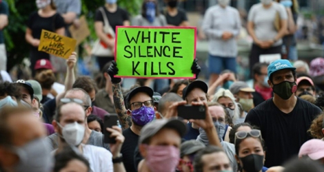 Des manifestants blancs, l'un armé d'une pancarte disant 