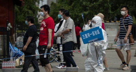 Un membre du personnel médical oriente les habitants proches du marché de Xinfadi vers le centre de dépistage, le 17 juin 2020 à Pékin.