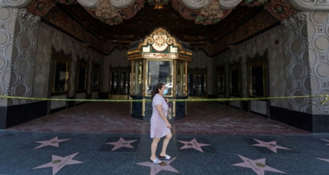 Une femme marche devant le fameux cinéma El Capitan à Hollwood, fermé à cause du coronavirus, à Los Angeles, le 12 juin 2020.