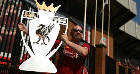 Un supporter de Liverpool pose avec un trophée factice après le sacre de Liverpool champion de Premier League, le 26 juin 2020.