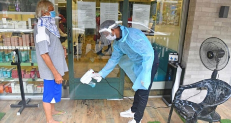 Un employé désinfecte les pieds d'un client avant qu'il entre dans un salon de coiffure, le 28 juin 2020 à Bombay, en Inde.