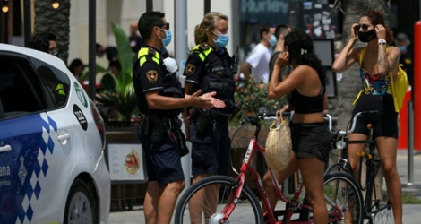 Des policiers municipaux demandent à des habitants de porter un masque de protection près d'une plage de Barcelone, le 9 juillet 2020.