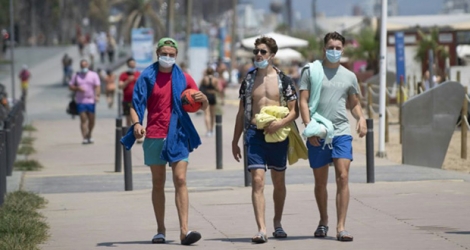 Des promeneurs avec les masques le long de la plage à Barcelone.