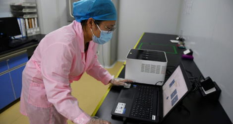 Une technicienne vérifie les résultats d'un test en utilisant le Flash 20, une machine conçue par l'entreprise chinoise de biotechnologie Coyote pour réaliser des dépistages rapides au nouveau coronavirus, le 27 septembre 2020 à Pékin.