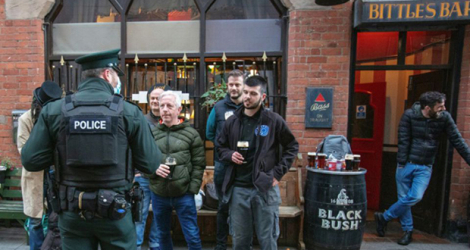 Un policier s'entretient avec les clients d'un bar à Belfast, en Irlande du Nord, le 16 octobre 2020.