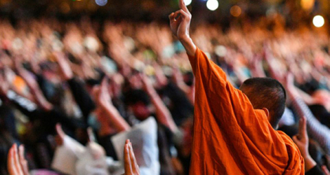 Des manifestants pro-démocratie, dont un moine bouddhiste, lèvent trois doigts en signe de résistance, le 18 octobre 2020 à Bangkok.