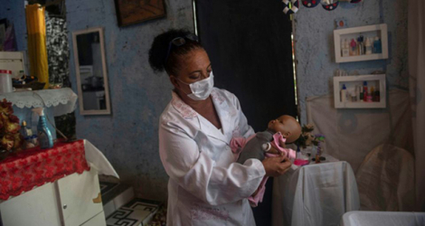 Suelen da Silva ausculte sa patiente, une poupée; qu'elle va restaurer, chez elle dans son «hopital de poupées» à Niteroi, près de Rio de Janeiro, le 10 décembre 2020.