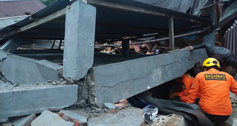 Les secours indonésiens fouillent les décombres d'un bâtiment effondré à Mamuju, sur l'île des Célèbes, frappée par un puissant séisme le 15 janvier 2021.