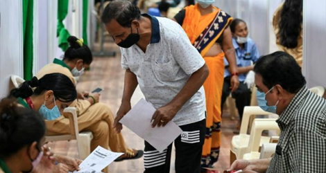 Un volontaire aide les patients à remplir un formulaire avant de se faire vacciner contre le coronavirus, à Bombay, le 1er avril 2021. afp.com - Punit PARANJPE
