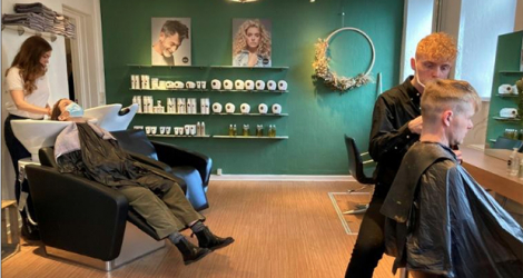 Des clients dans un salon de coiffure du centre de Copenhague, le 6 avril 202. Le Danemark a commencé à exiger que les gens utilisent une nouvelle application Covid pour pouvoir accéder à certains commerces sous peine d'amende, une première en Europe. afp.com - Camille BAS-WOHLERT
