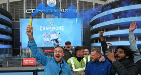 Les supporters de Manchester City en liesse devant leur stade après le sacre de champion de leur équipe consécutif à la défaite de Manchester United, le 11 mai 2021. afp.com - Paul ELLIS