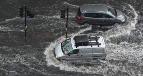 Des voitures roulent sur des chaussées inondées dans le quartier de Nine Elms à Londres, le 25 juillet 2021 - AFP