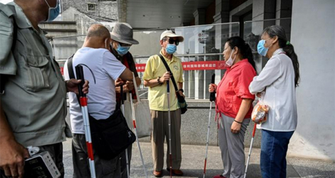 Des personnes aveugles ou malvoyantes à l'entrée d'un cinéma, le 7 août 2021 à Pékin, en Chine.