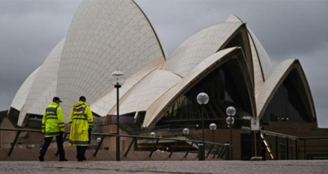 Des policiers devant l'opéra de Sydney le 10 octobre 2021, à la veille de la levée du confinement dans la plus grande ville d'Australie.